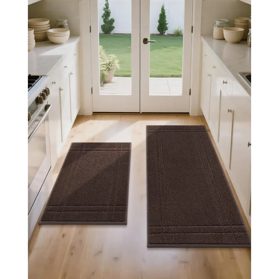 Brown kitchen rugs on a wooden floor with white cabinets and a glass door leading outside.