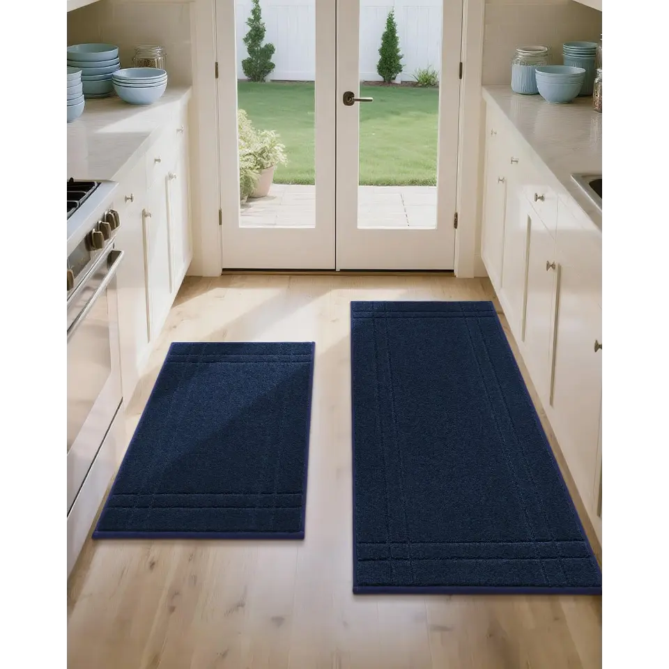 Two navy blue kitchen mats on a wooden floor with a view of a garden through French doors.
